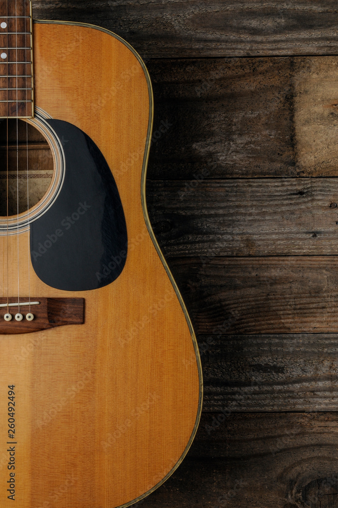 Fototapeta premium An acoustic guitar on grunge wood background to use as book cover for a guitar course