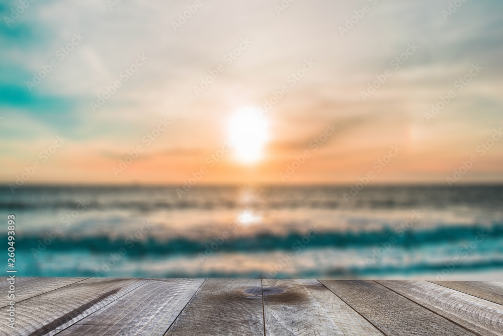 Top of wood table with blurred sea and sunset.