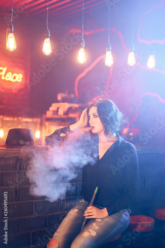 beautiful girl in a black hat and jeans near the bar stand amid smoke and hay and red lighting 1