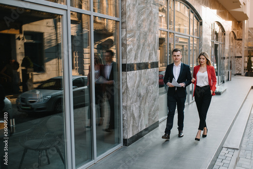 A two young business-people are walking along office building