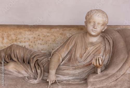 Ancient roman statue of boy resting on a divan