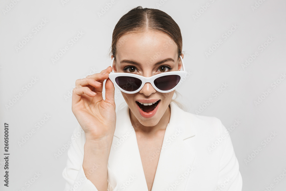 Beautiful happy woman posing isolated over white wall background wearing sunglasses. Beautiful happy woman posing isolated over white wall background wearing sunglasses.