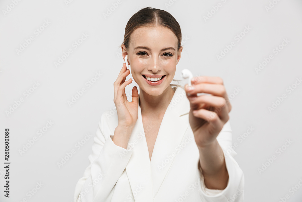 Beautiful amazing woman posing isolated over white wall background listening music with earphones. Beautiful amazing woman posing isolated over white wall background listening music with earphones.