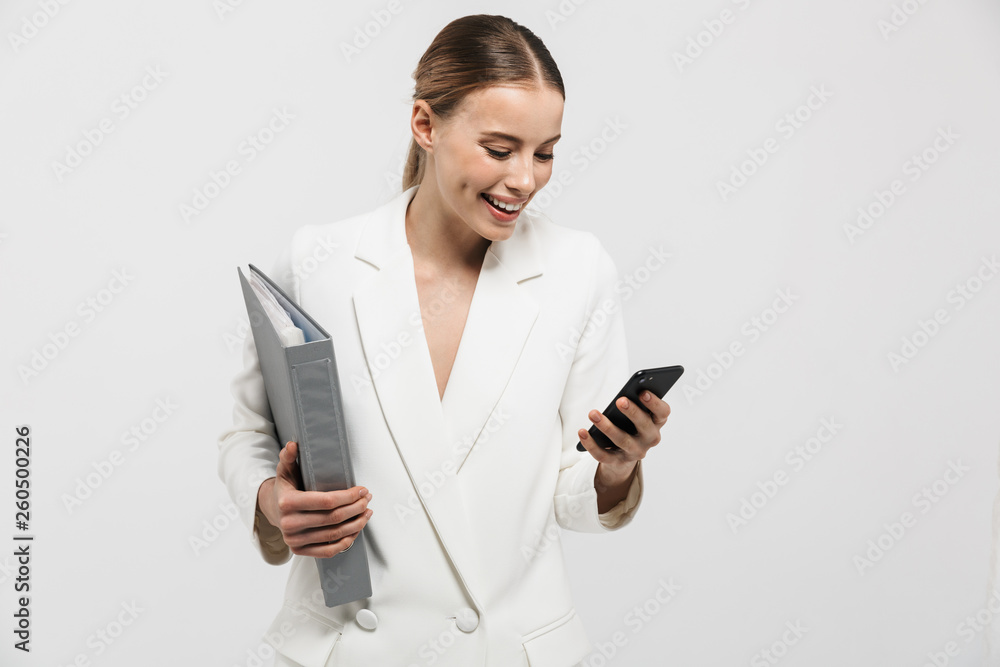 Beautiful amazing woman posing isolated over white wall background holding folder talking by mobile phone. Beautiful amazing woman posing isolated over white wall background holding folder talking by mobile phone.