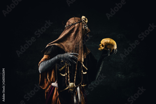 Portrait of a shaman holding a human skull in his hands photo