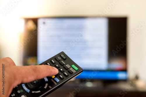 Black remote control. TV is blurred background
