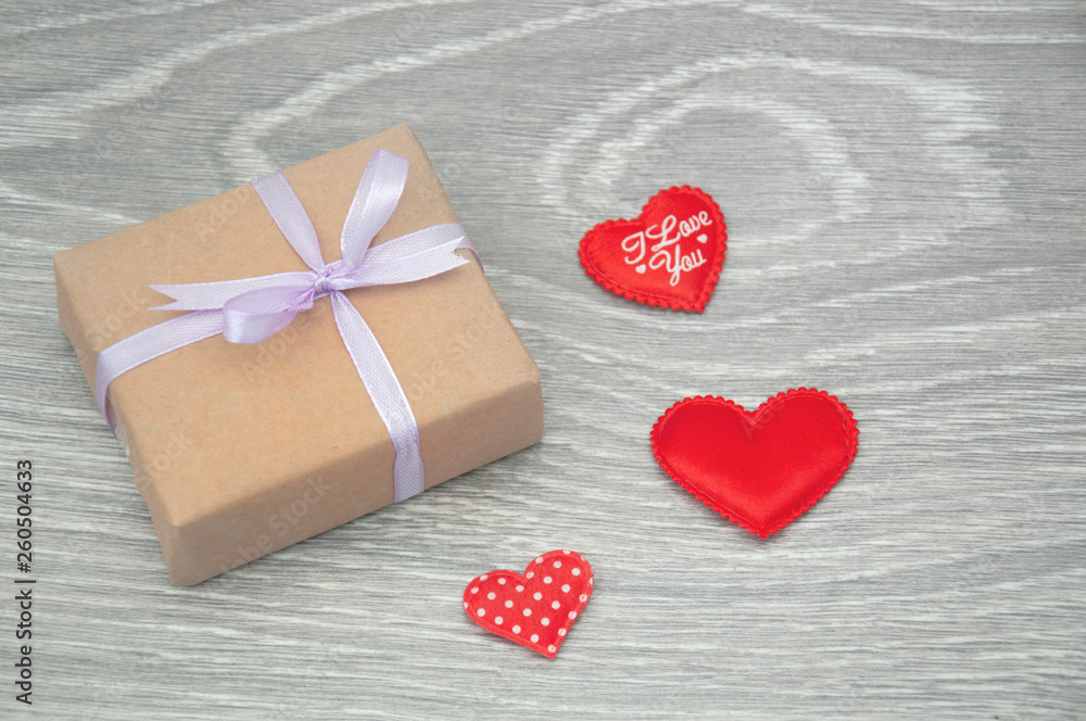 Fototapeta premium Gift box with red hearts on gray wooden background. Greeting card for Valentine's Day.