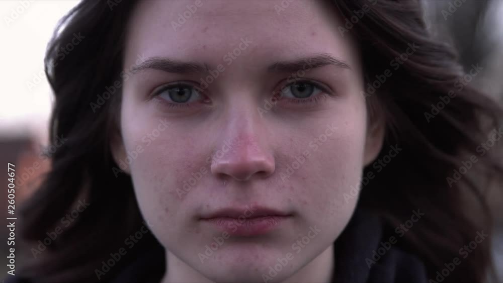 Face of a girl with her hair waved by wind closeup. She is looking at the camera. Face of a girl with her hair waved by wind closeup. She is looking at the camera.