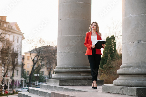 Portrait of business women in feeling of concentrate stress and see stand and hold the paper file sheet in the outdoor pedestrian walk way with the city space of exterior modern facade building