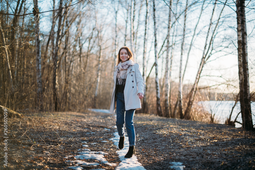 Fototapeta premium A girl walks along a forest trail through the last snow.