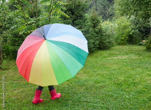 Child walks under umbrella in a rain outdoors