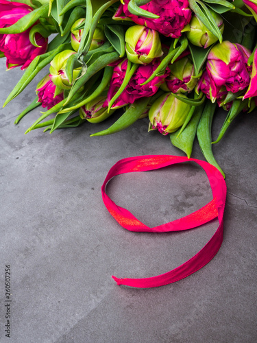 red tulips with red ribbon isolated on concrete background. Victory day or Fatherland defender day.