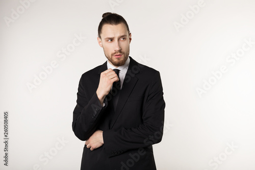 Handsome businessman wearing black suit and tie looking stressed and nervous with hand near face