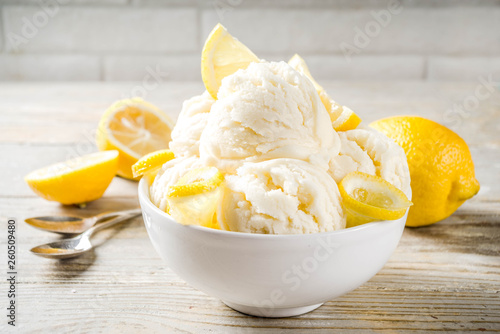 Homemade lemon vanilla ice cream with fresh lemon slices. Sweet and sour summer dessert. Wooden background copy space photo