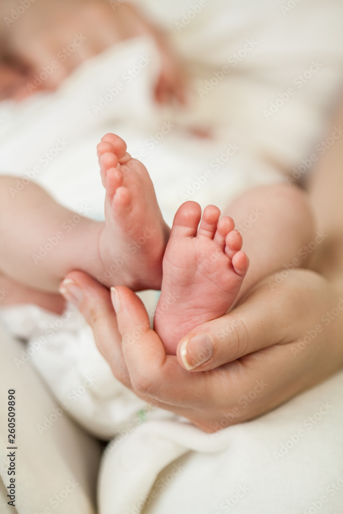 Close-up. The legs of the little baby in her mother's arms. Motherhood. Close-up. The legs of the little baby in her mother's arms. Motherhood.