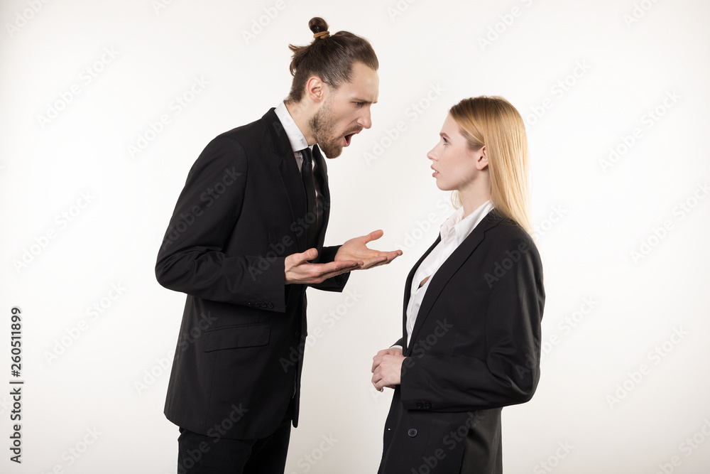 Attractive businessman with beard and trendy hairstyle in black suit screaming at his subordinate who can't cope the task Attractive businessman with beard and trendy hairstyle in black suit screaming at his subordinate who can't cope the task