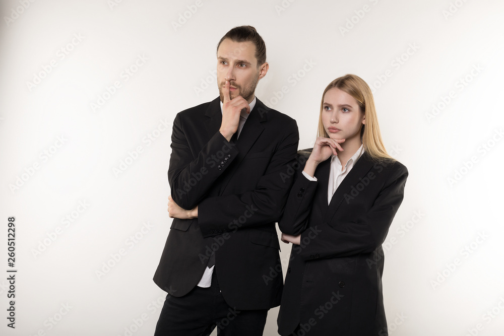 Two business partners in black suits, handsome bearded man and beautiful blonde woman thinking about solving the probleme at work Two business partners in black suits, handsome bearded man and beautiful blonde woman thinking about solving the probleme at work