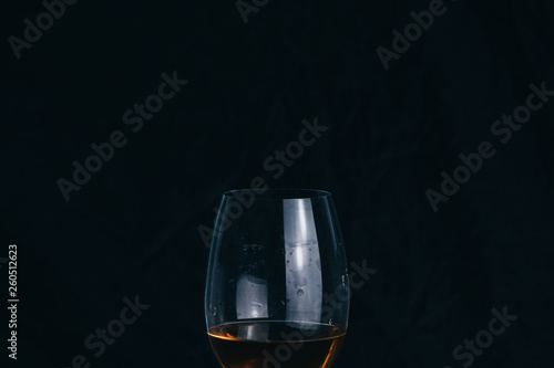 cropped glass of white wine on a black background. rest, holiday, party. isolated alcoholic drink closeup.