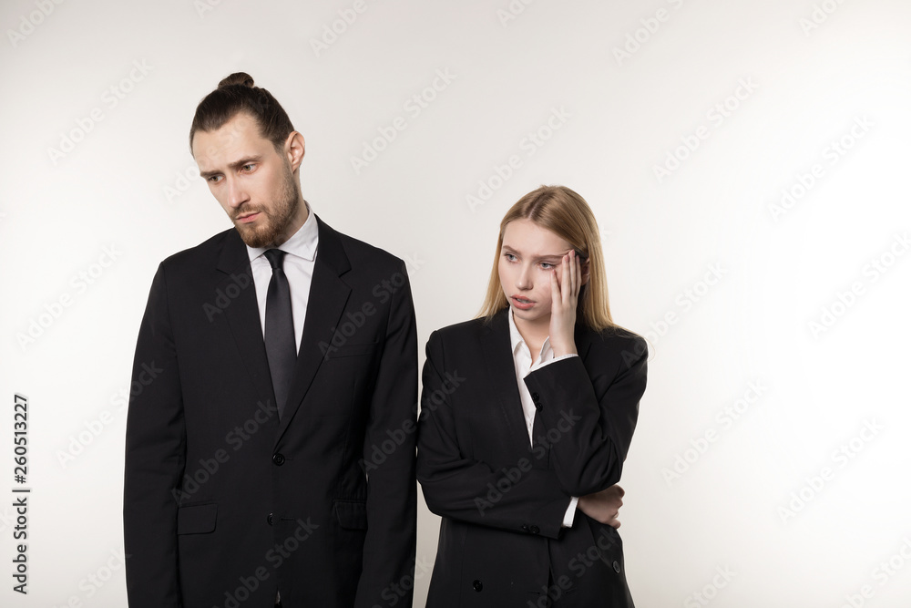 Two business partners in black suits, handsome bearded man and beautiful blonde woman shocked don't know what to do Two business partners in black suits, handsome bearded man and beautiful blonde woman shocked don't know what to do