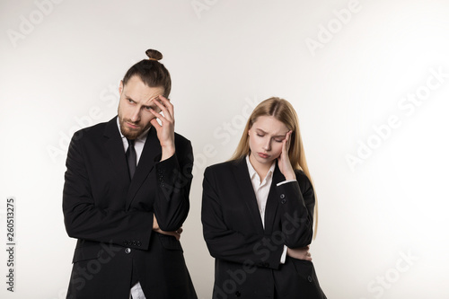 Upset business couple wearing black suits over white background, working together
