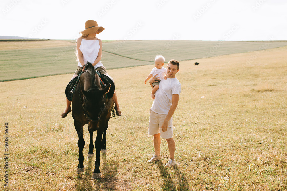 A young family have a fun in the field. Parents and child with a horse
