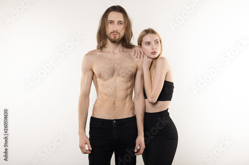 Young serious beautiful woman in black skirt and man in black jeans and with naked torso