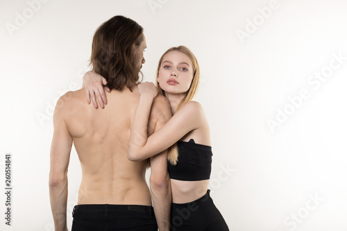 Heterosexual couple, handsome man with long hair and naked torso and his beautiful girlfriend in black skirt hugging