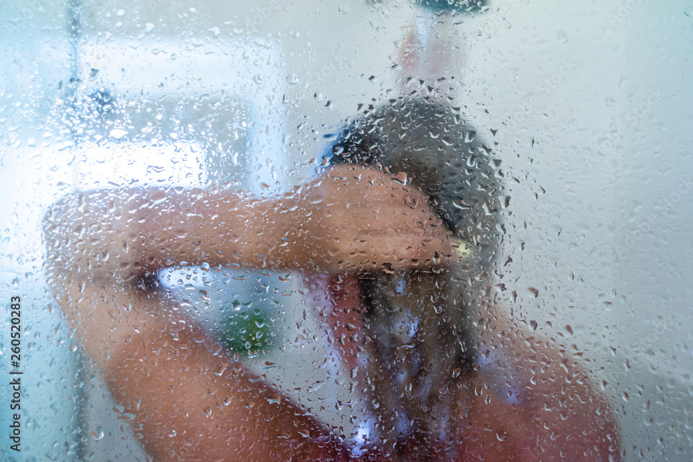 woman in the shower behind glass with drops