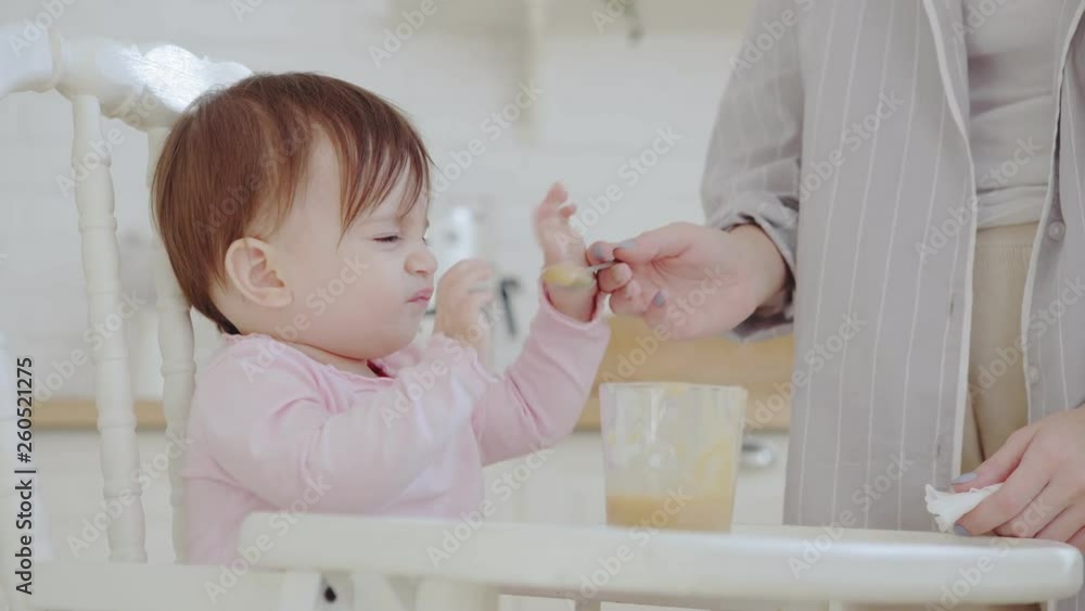 Cute baby girl refusing to eat fruit puree, but her patient mother ...