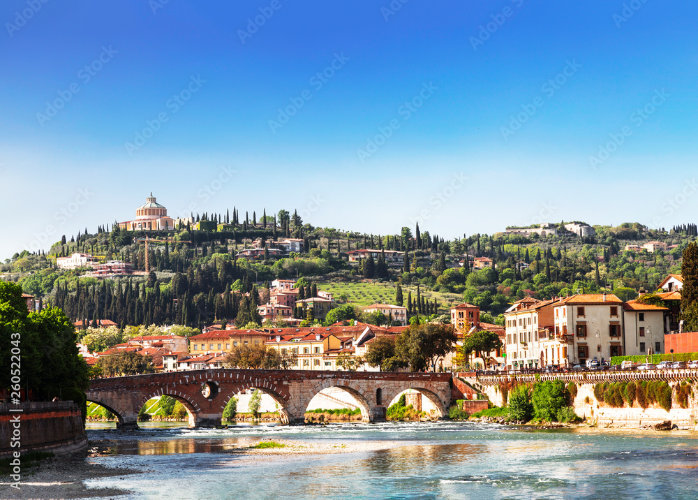 View of Verona with Ponte Pietra bridge over the Adige river and the Sanctuary of our lady of Lourdes on a hill, Italy