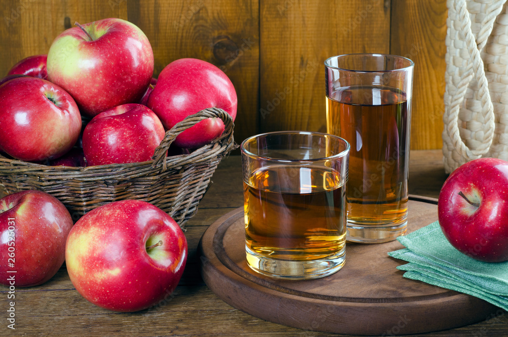 Apple juice in glasses and red apples in a basket. Apple juice in glasses and red apples in a basket.