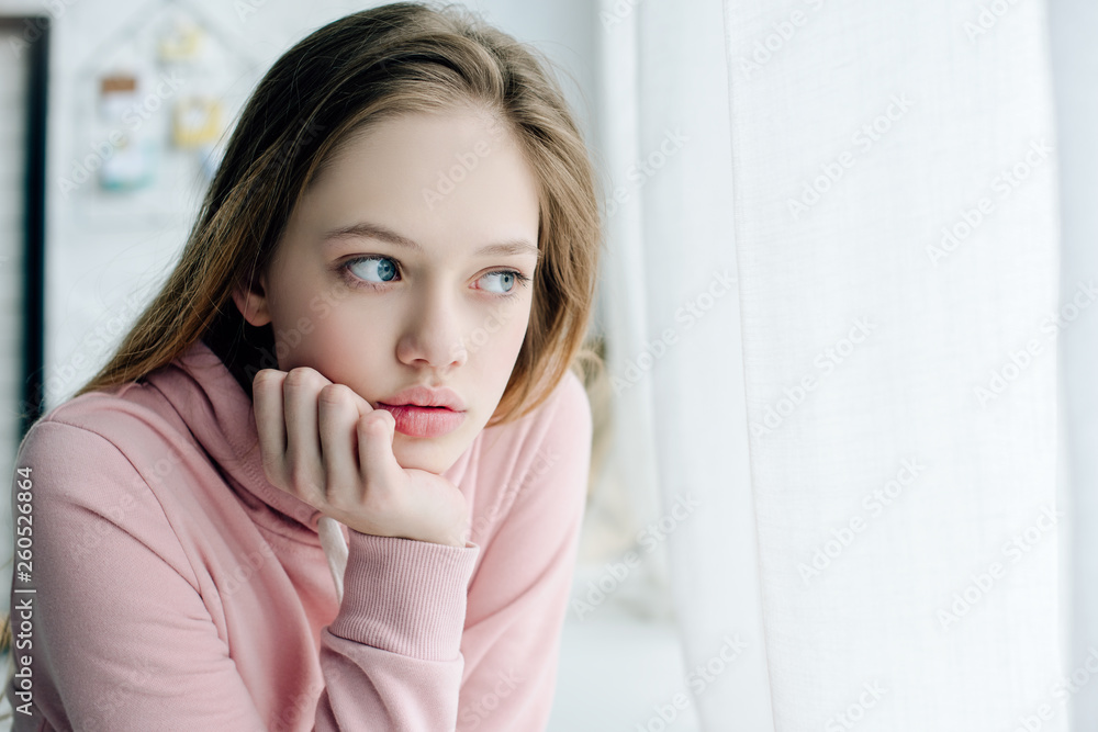 Pensive teenage propping face with hand and looking away Pensive teenage propping face with hand and looking away