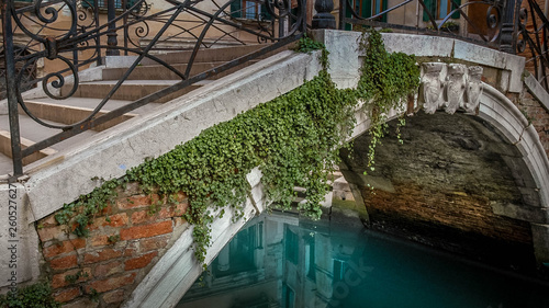 Bridge over a canal in Venice showing building reflections with ironwork railings