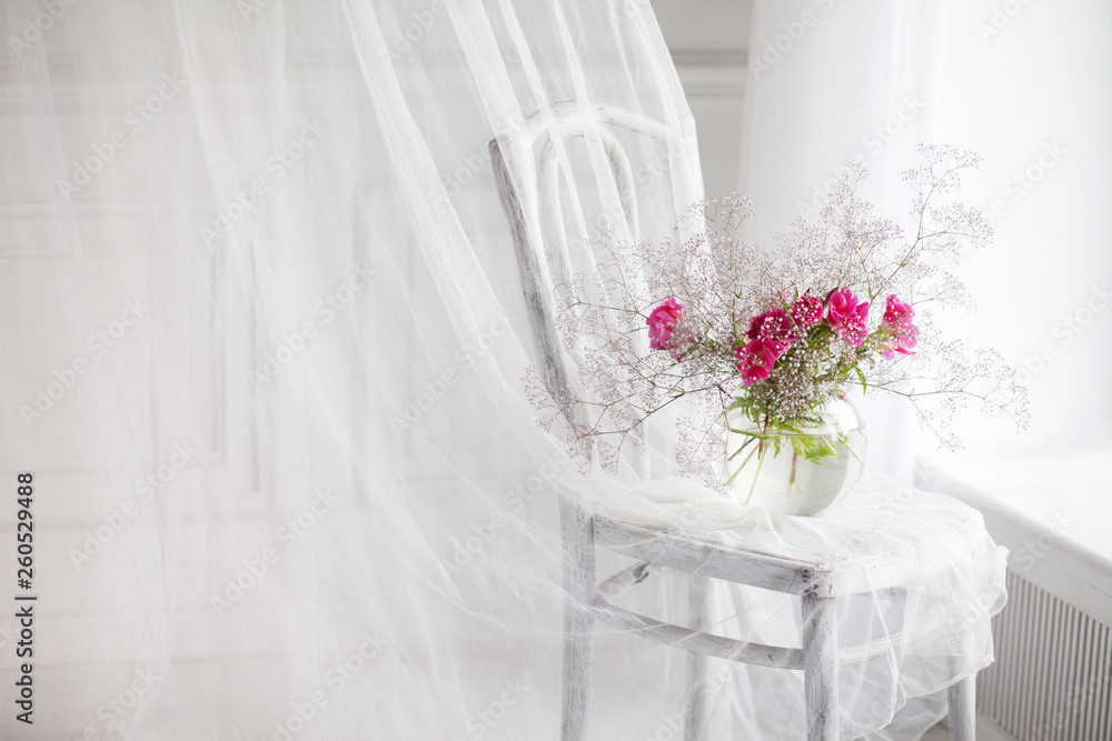 Still life with gipsofila and rose flowers in glass vase on retro chair Still life with gipsofila and rose flowers in glass vase on retro chair