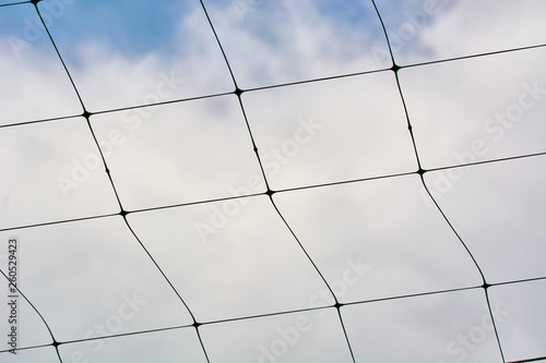 Beautiful volleyball net against the blue sky with clouds.