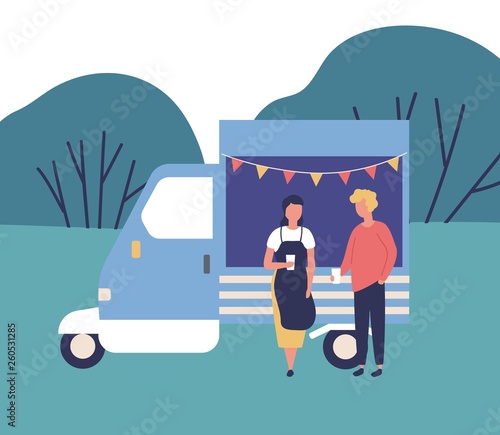 Cute young man and woman standing beside food truck, drinking coffee and talk...