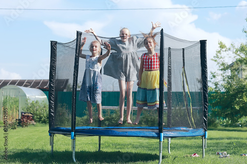 children jumping on a trampoline, girlfriends having fun in the summer in a recreation park on a trampoline