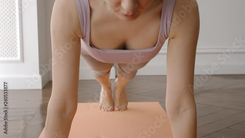 REAL TIME: Young Woman in sportsuit standing in the plank on a yoga mat at home photo