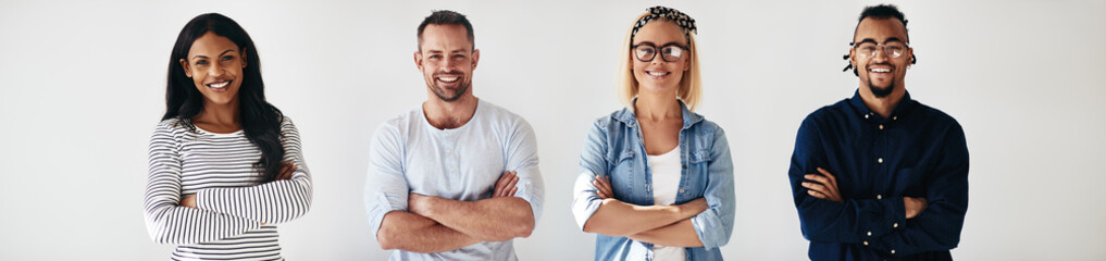 Diverse group of smiling colleagues standing with their arms cro