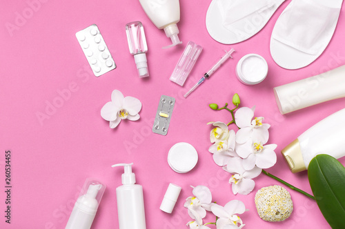 Spa concept cosmetology medicine plastic surgery branding mock-up. White cosmetic bottle gloves slippers hygiene items gasket tampon cotton pads injections tablet orchid on pink background flat lay
