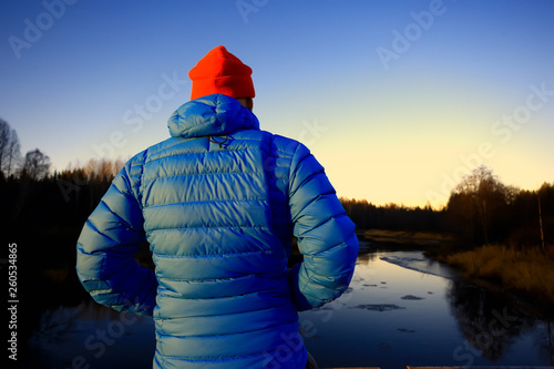 man in sports down jacket landscape winter trekking / down jacket on a tourist, outdoor activities in the north, seasonal landscape