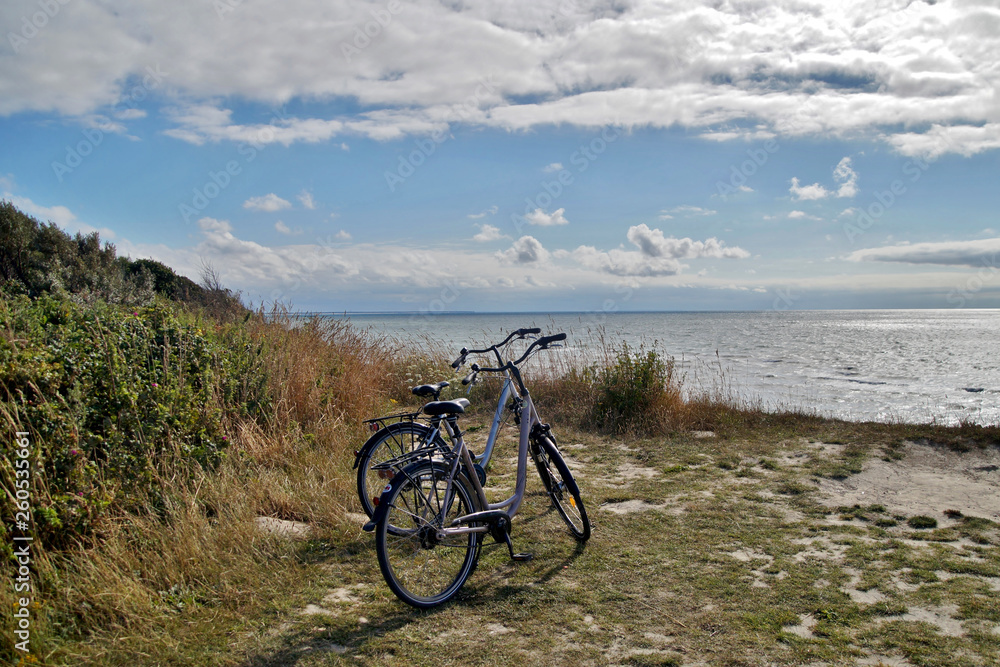 view of two bicycles parked and a view of a beach on a sunny Day, Baltic Sea Germany, bicycles on sea cliffs on the Coastal footpath with sky background and sea