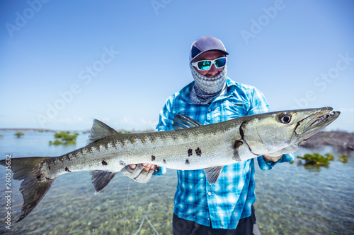 Fly fisherman holding a barracuda for a photo before releasing it. Cuba photo