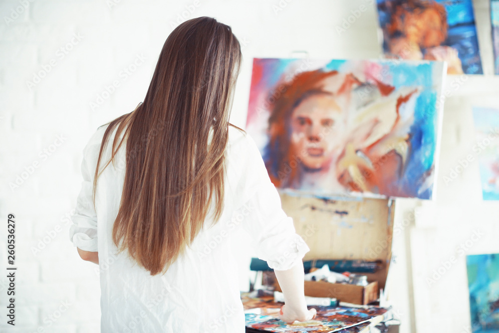 Fototapeta premium Young artist girl at work in the workshop brush paints canvas inspiration