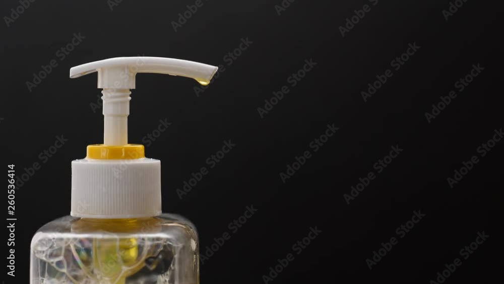 Man push dispenser and liquid detergent squeezed to sponge for manual dish washing, typical kitchen routine. Close up shot of plastic pump on small bottle against black background Man push dispenser and liquid detergent squeezed to sponge for manual dish washing, typical kitchen routine. Close up shot of plastic pump on small bottle against black background