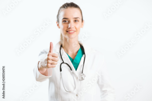Young smiley nurse puts thumb up, wears scrub uniform and stethoscope.