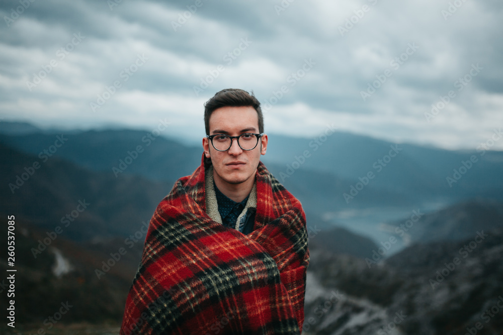 Young Man Wrapped in Checkered Warm Blanket Enjoying on Mountain Top
