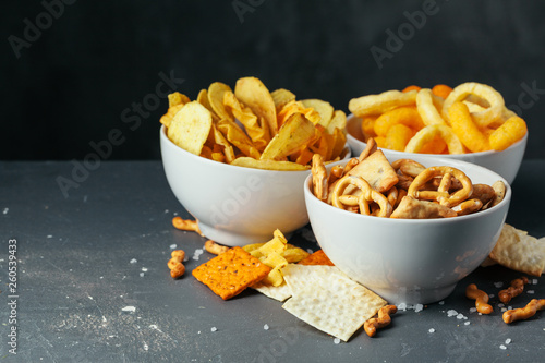 Beer snacks on stone table. Various crackers, potato chips. Top view