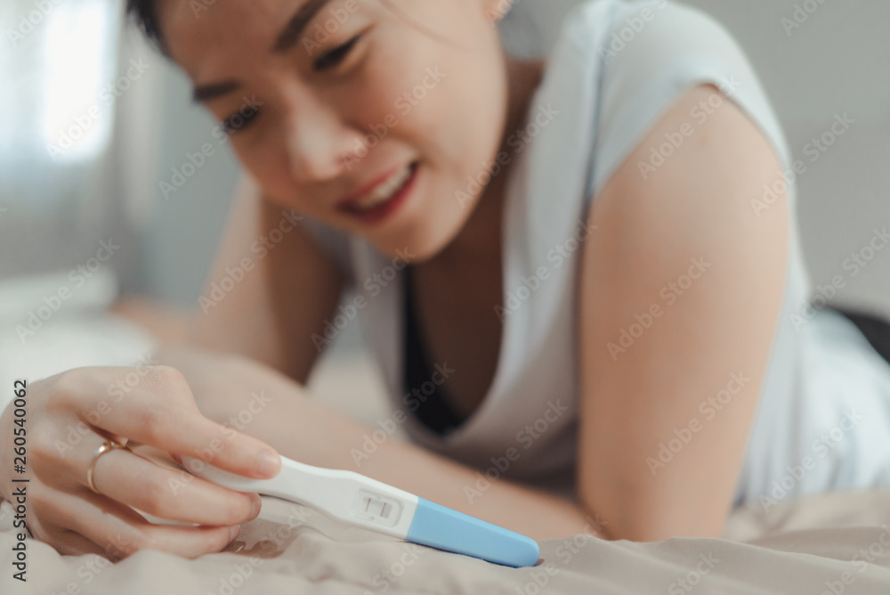 Young asian woman looking at pregnance test in happiness.Pregnancy family concept Young asian woman looking at pregnance test in happiness.Pregnancy family concept