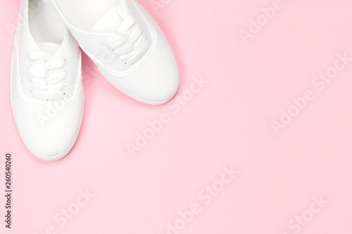 White beautiful women's sneakers on a pink background, copy space, concept shoes